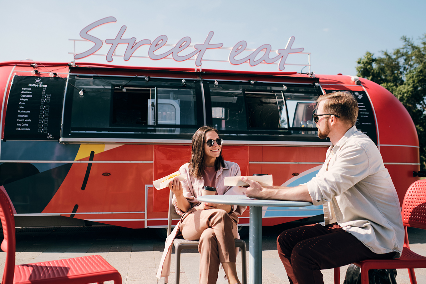 Two people sitting at a table outside a cafe.