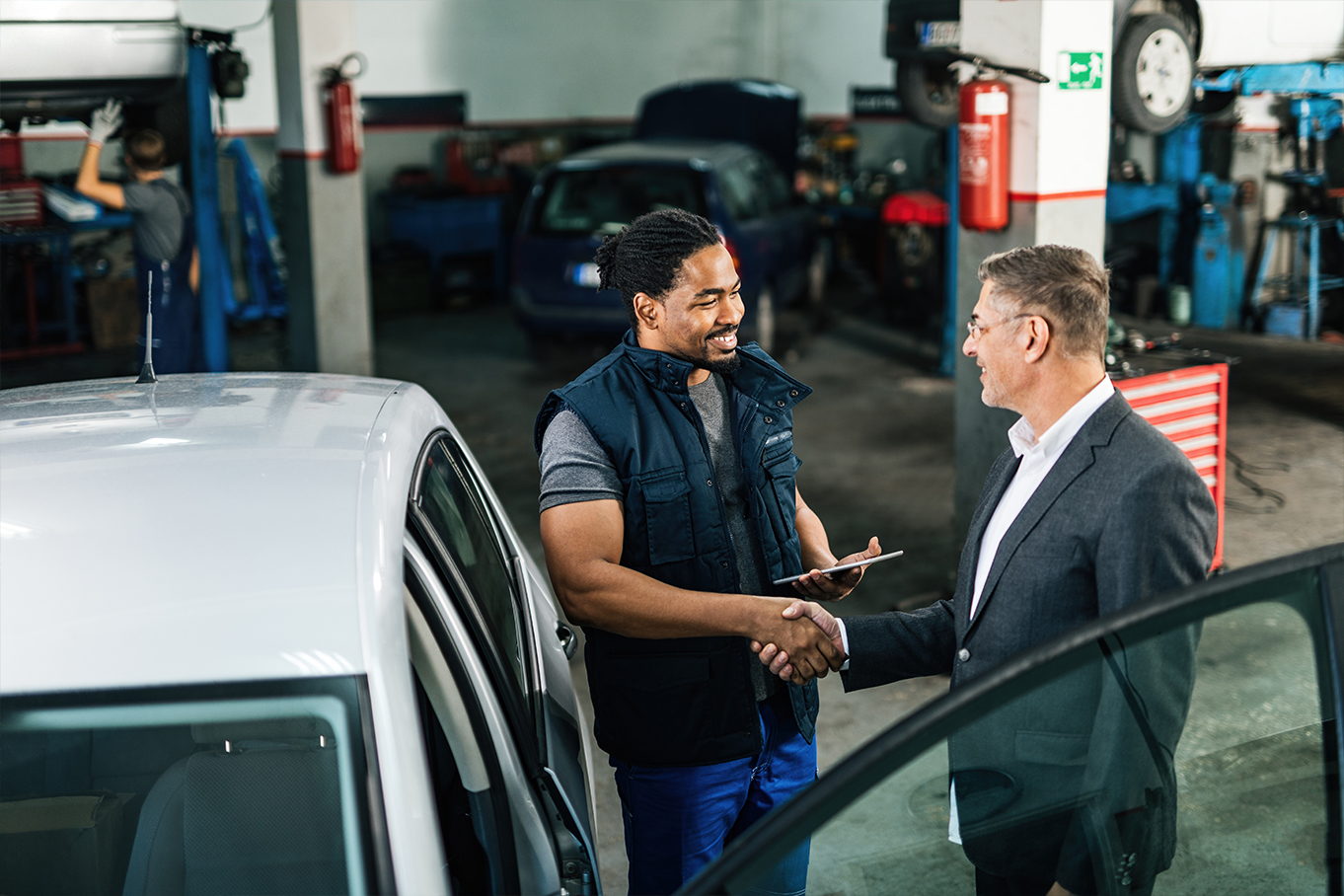 Two men talking at a car garage.