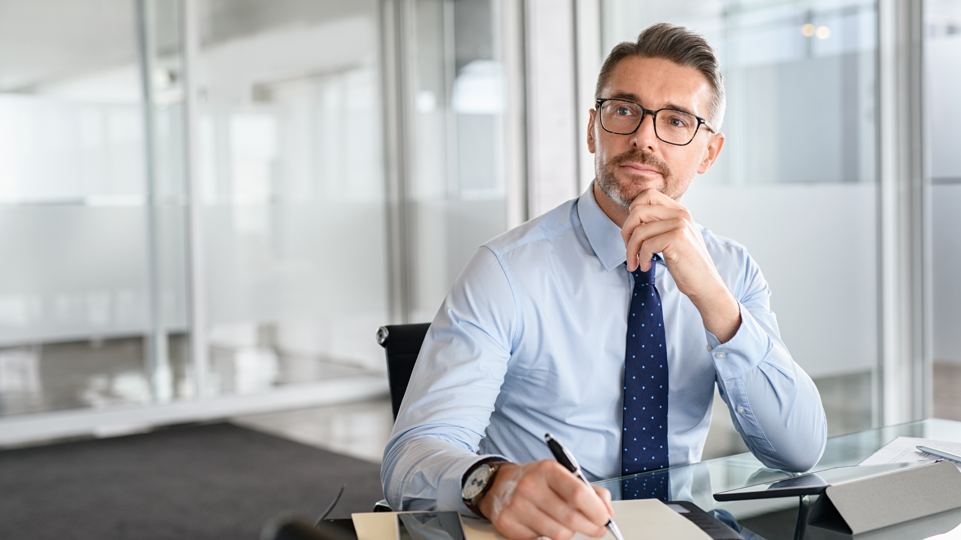 A man sitting at his office desk, thinking